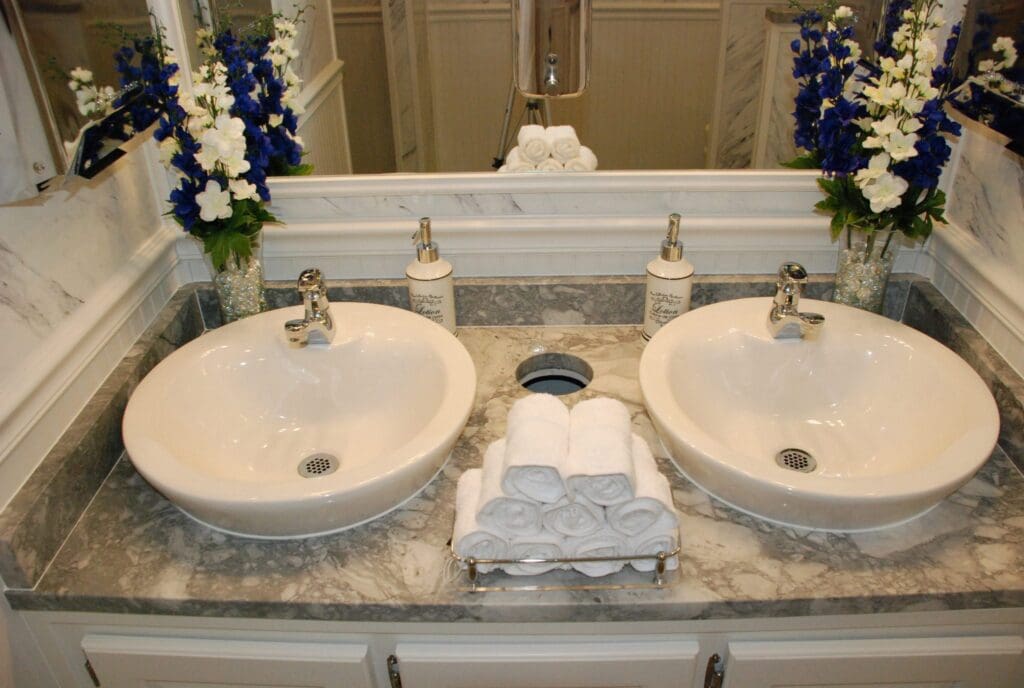 Double vessel sinks on a marble vanity with fresh flowers and rolled towels