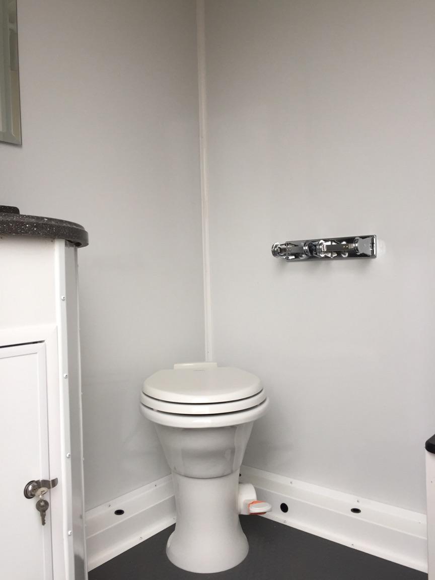 Inside view of a stall and sink of Six Station Restroom Shower Combo Trailer