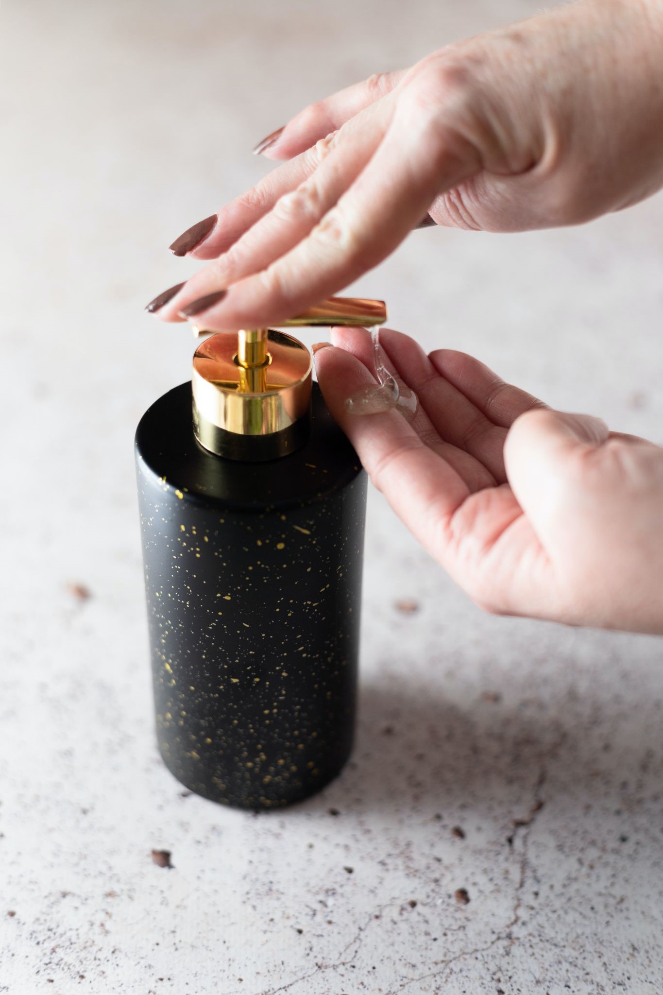 Woman using a sanitizer from a marble counter