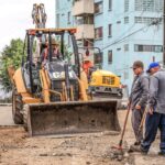 workers and construction vehicles at road building site